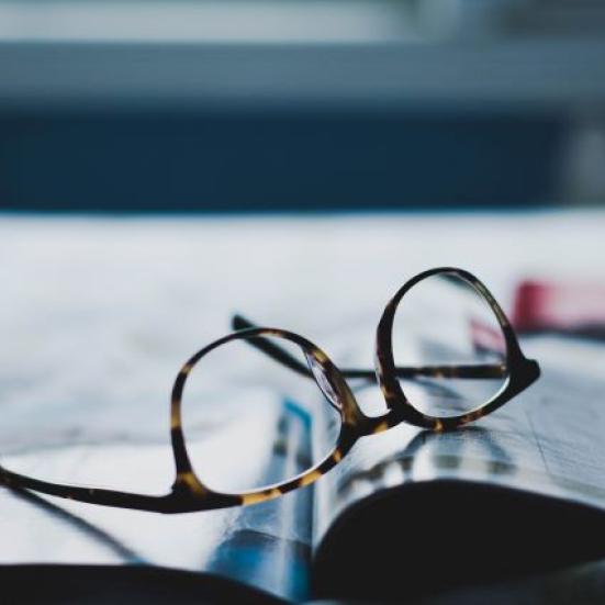 En opslået bog på et bord, med et par briller 