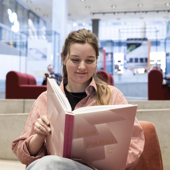 Kvinde der læser i en bog på biblioteket
