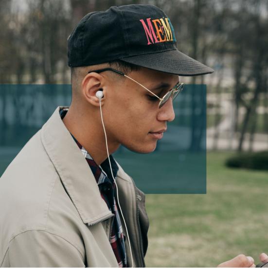 En mand har AirPods i ørerne og ser ned på sin telefon.