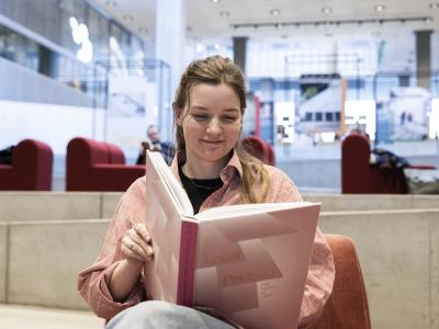 Kvinde der læser i en bog på biblioteket