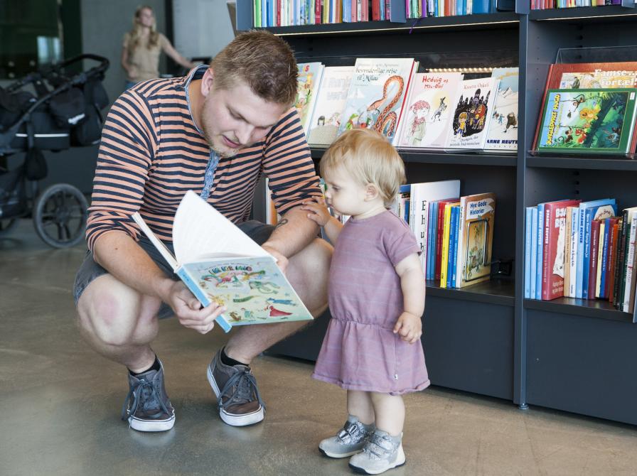 Far viser bog frem til hans lille datter.