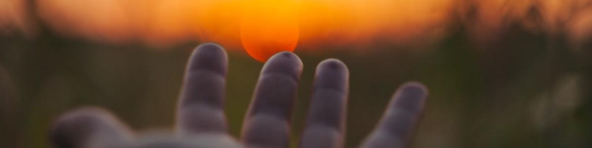 Billede af hånd, der rækker ud mod solopgang