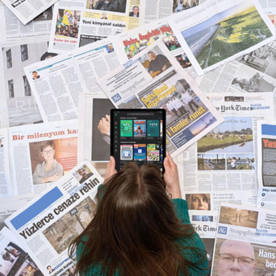 Kvinde med ryggen til kameraet læser avis på en tablet