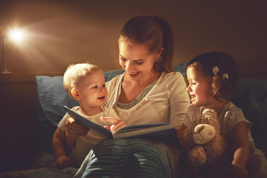 Kvinde der læser højt for to børn i en sofa