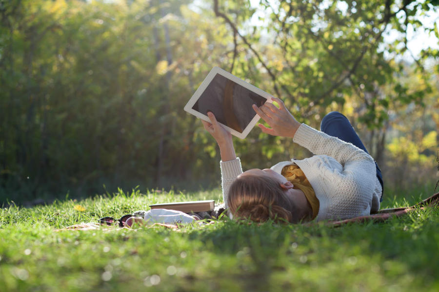 Kvinde der ligger og læser en ebog