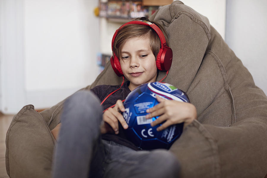 Dreng med fodbold lytter til en lydbog