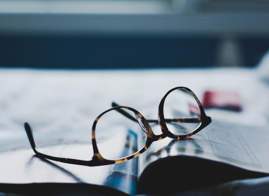 En bog der ligger på et bord sammen med et par briller