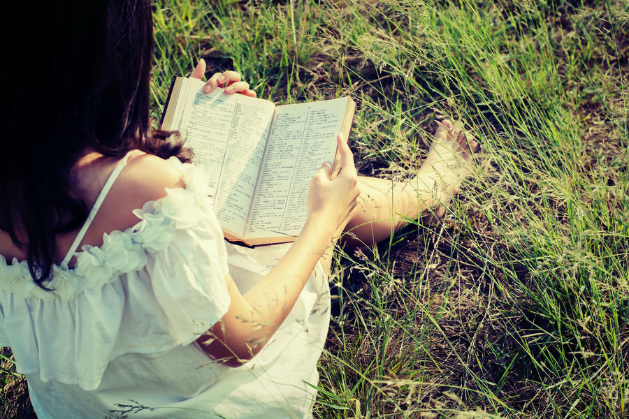 Ung kvinde i sommerkjole læser i en bog