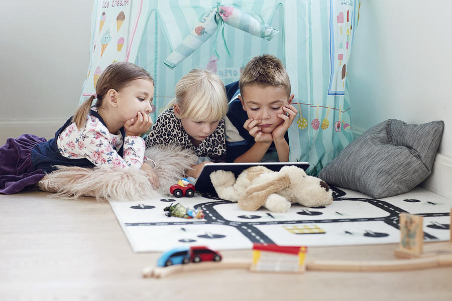 Tre børn læser på en ipad
