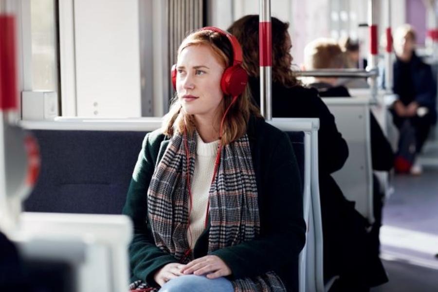 En kvinde sidder og lytter til en lydbog i toget