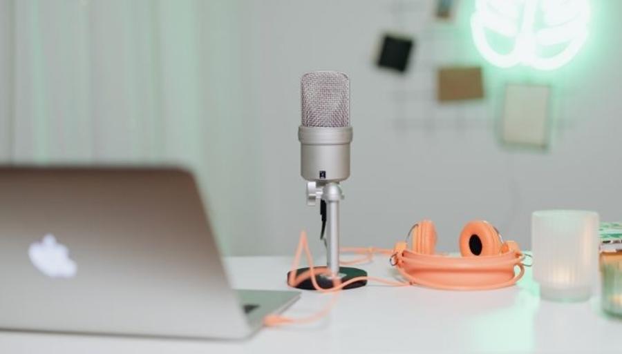 Mikrofon, computer og høretelefoner på et bord