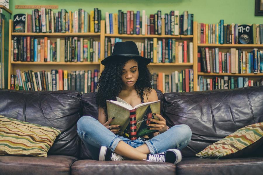 Ung kvinde sidder i en sofa med en bog