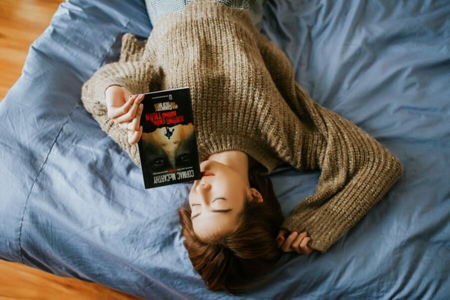 Ung person ligger på gulvet med en bog